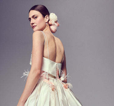 Model wearing an elegant backless dress with floral details.